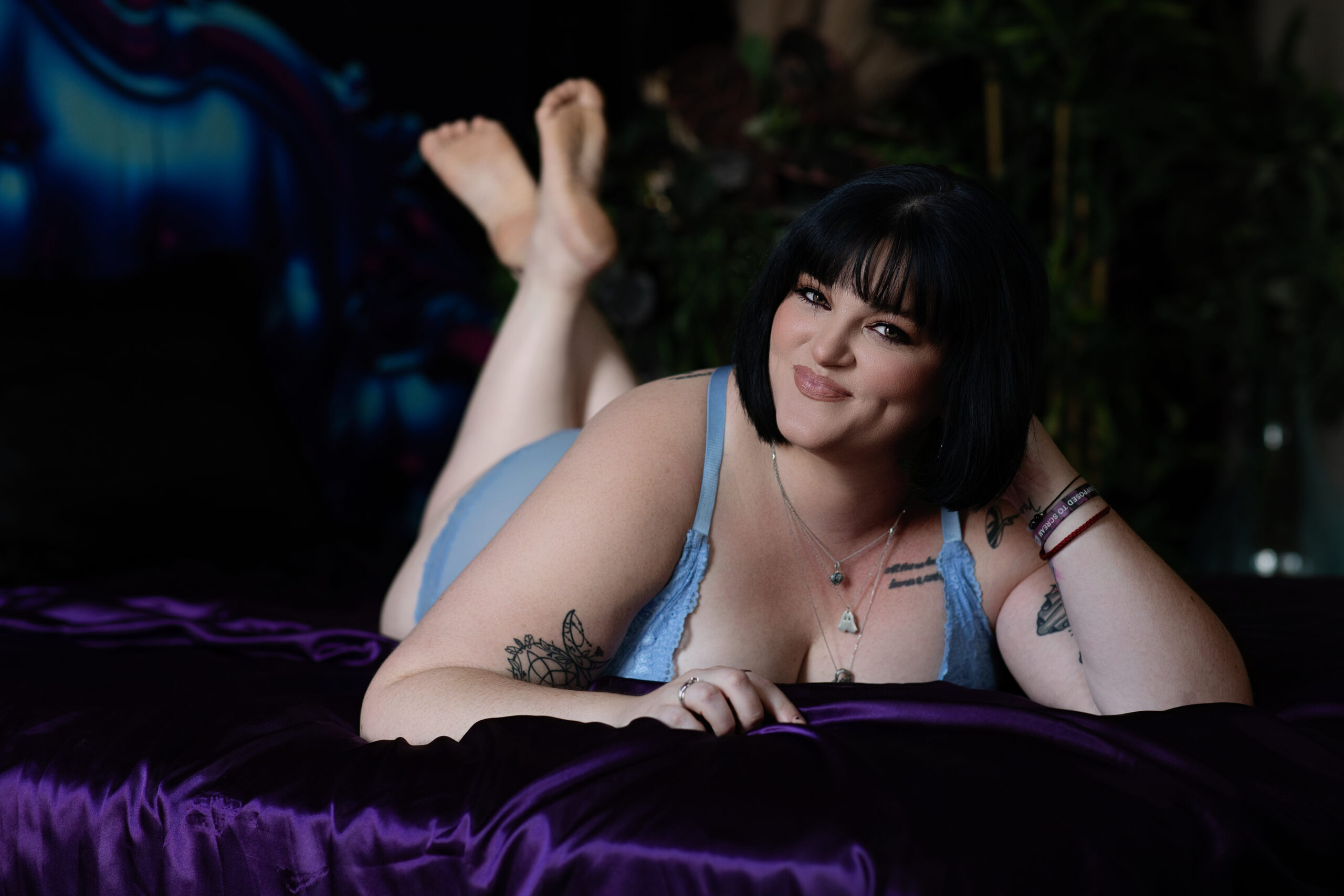 woman laying on bed in a purple sheet, crimson and ivy studio