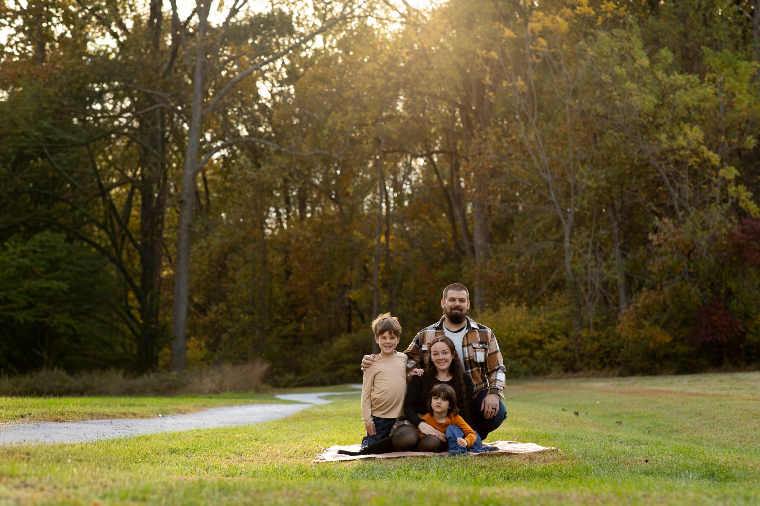 Cozy family portrait on a blanket surrounded by autumn trees during golden hour at Hibernia Park Coatesville Pennsylvania